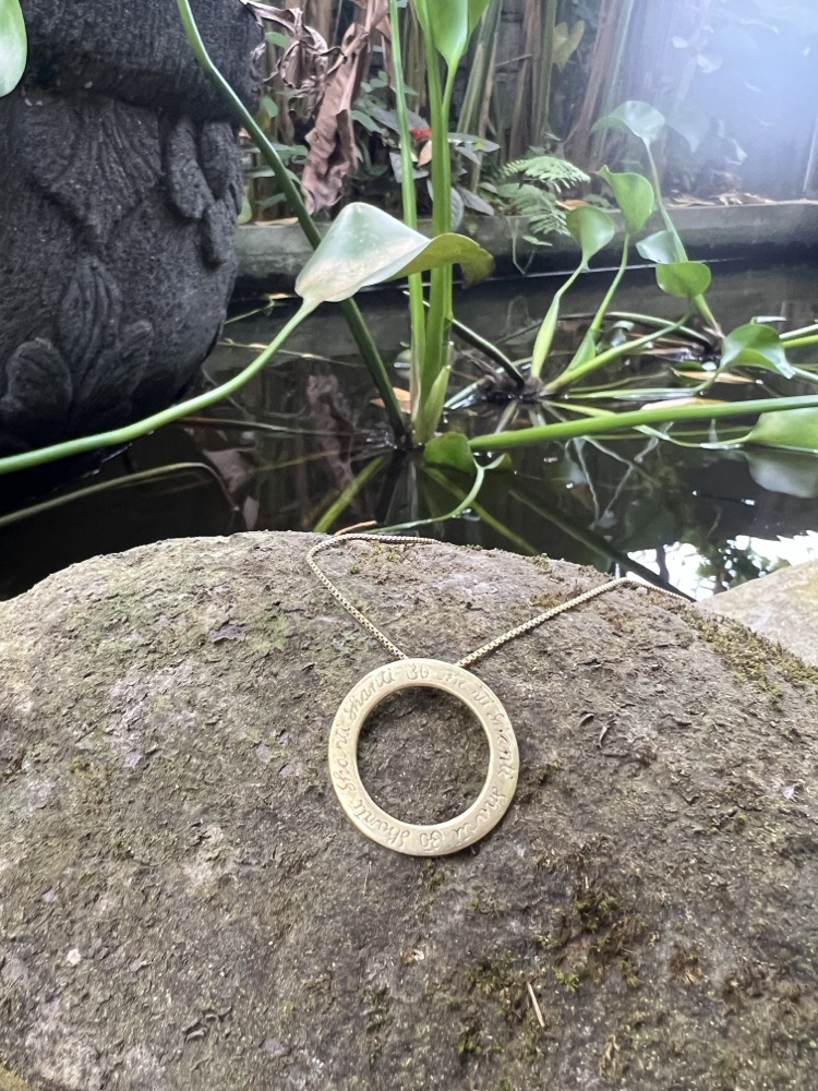 The necklace on a mossy stone beside a carved Balinese stone figure